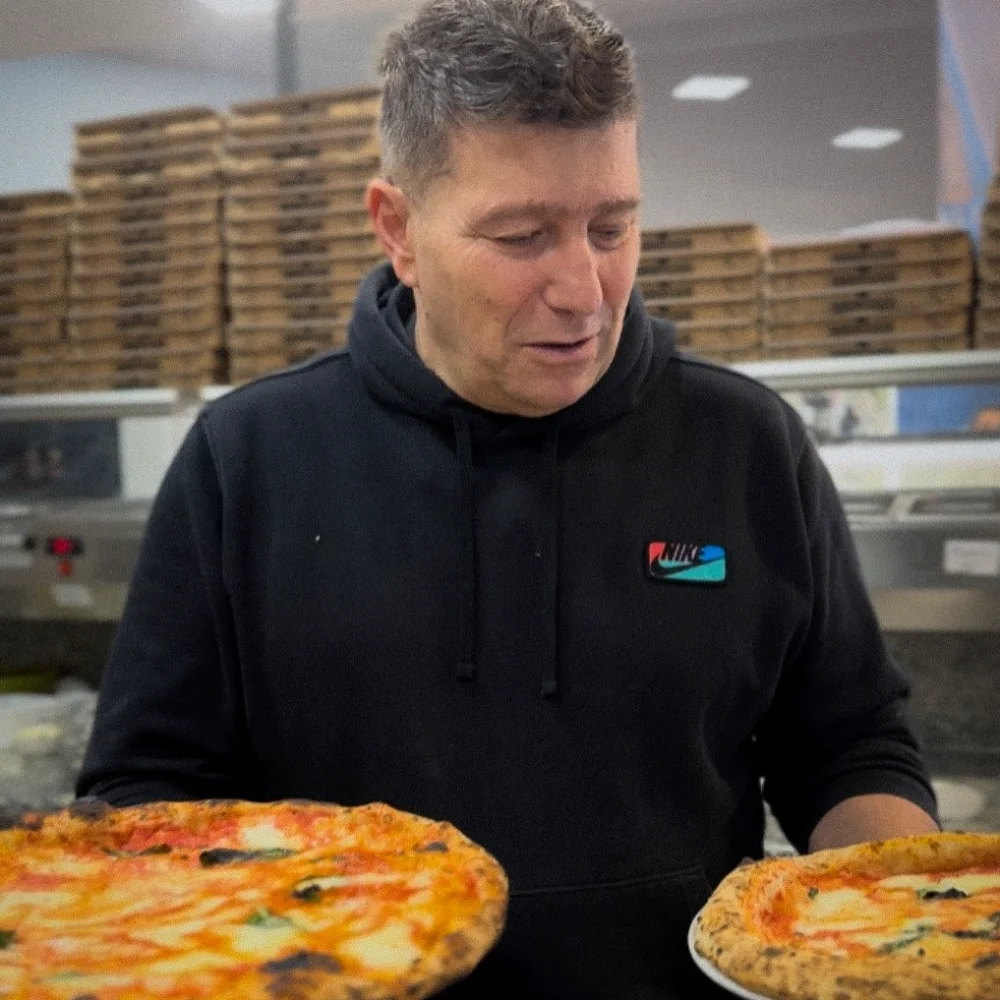 Il pizzaiolo di Vera Napoli con due pizze napoletane appena sfornate