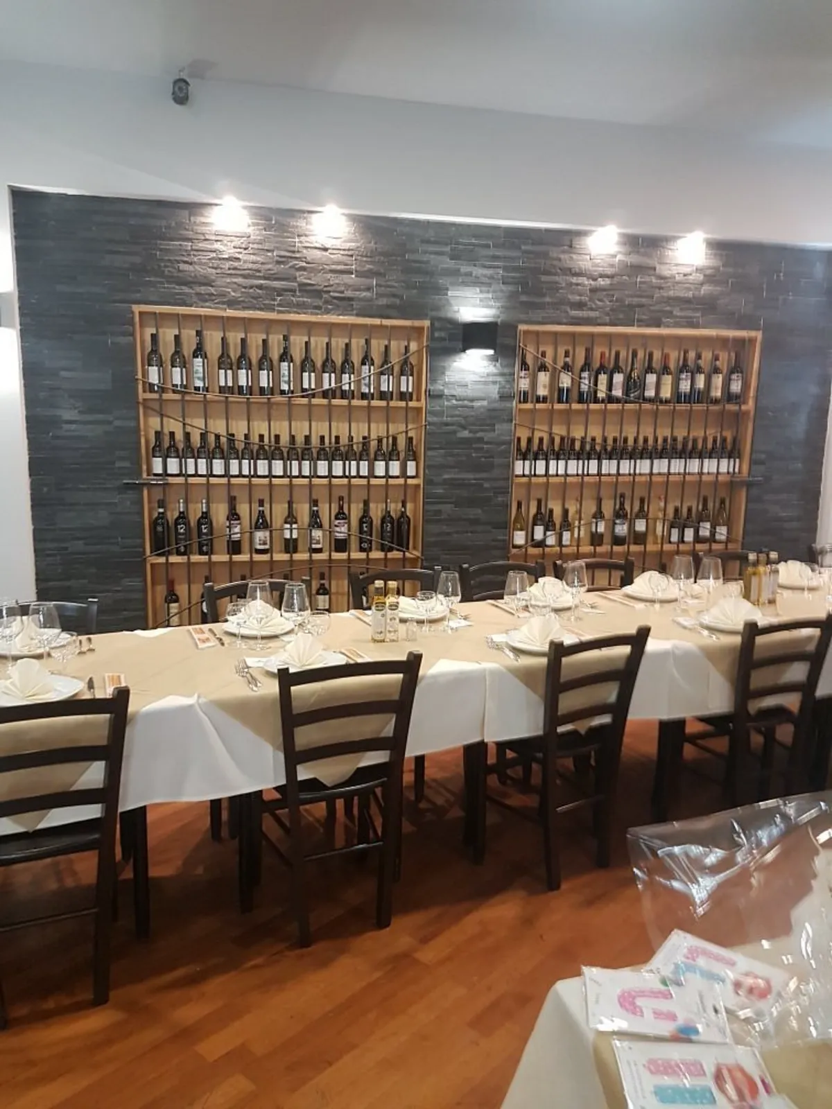 La sala di Vera Napoli con i tavoli apparecchiati e la parete dei vini
